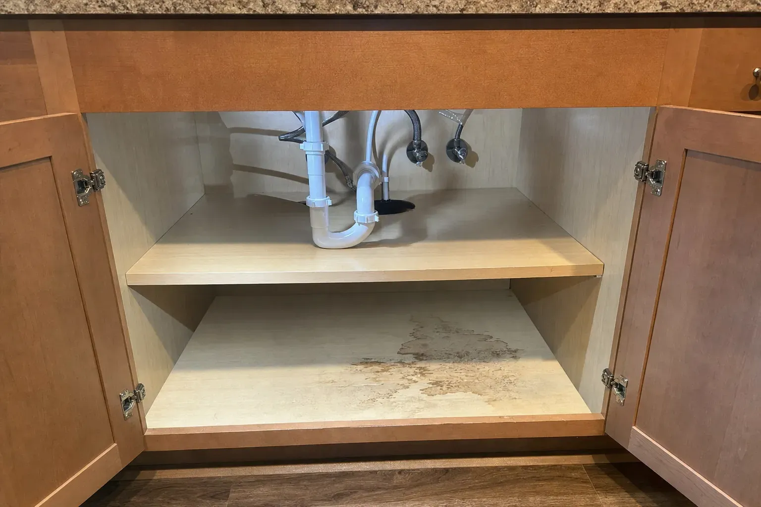 Open kitchen sink cabinet with plumbing lines reviewed during a York Pennsylvania mold inspection.